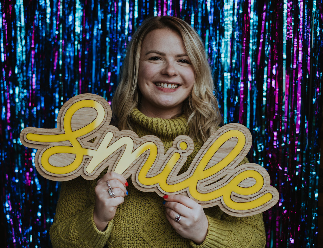 UK Based Designer, Sam holding a Wooden Smile Sign - Meet The Maker Image